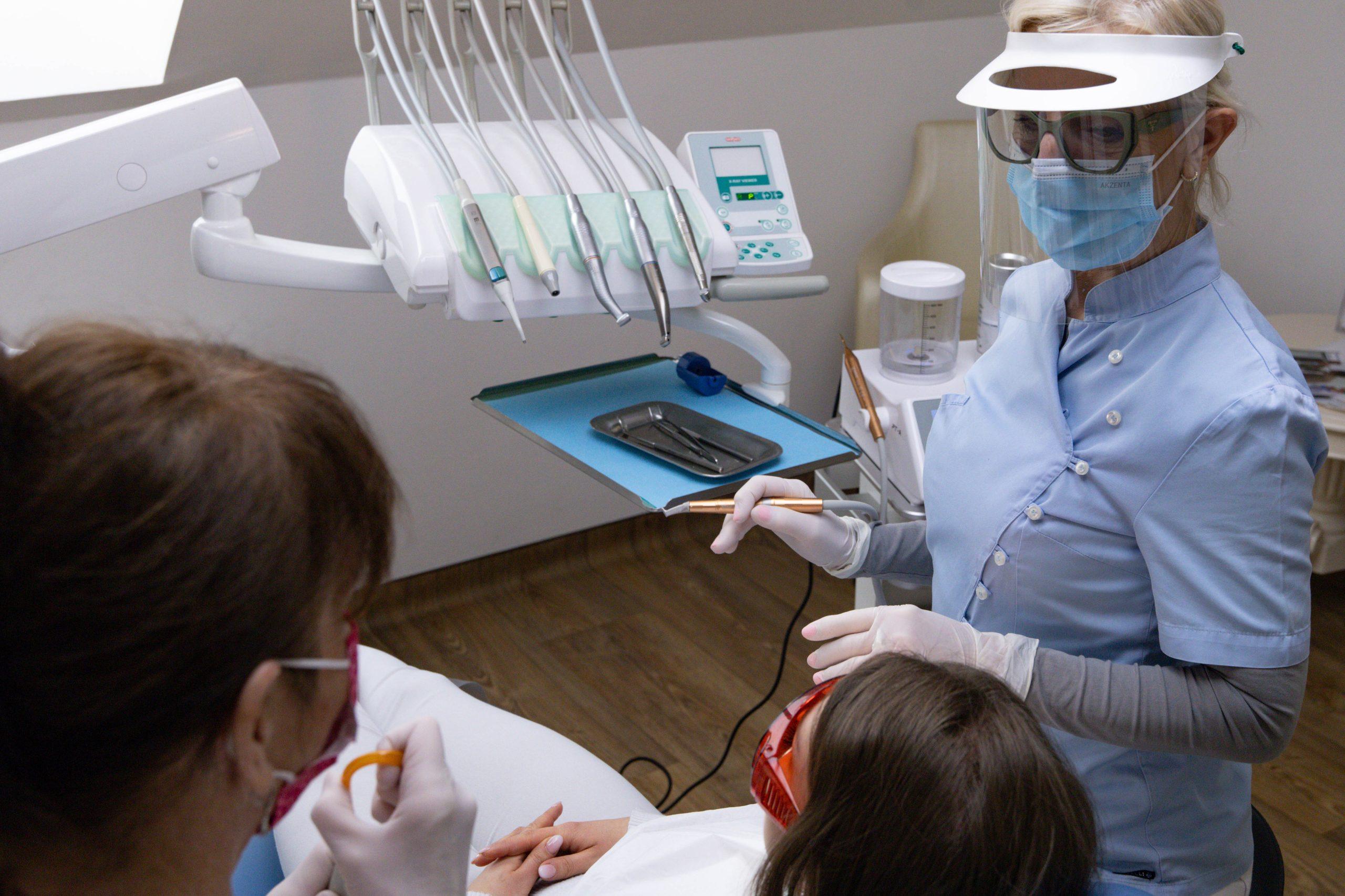 Fogászati kezelés közben fogorvos és asszisztens dolgozik páciensen modern kezelőszékben a budapesti Centrocc Dental rendelőben